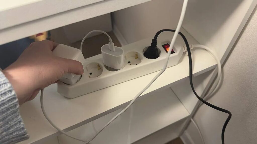 Mano che scollega la spina del microonde dalla presa elettrica